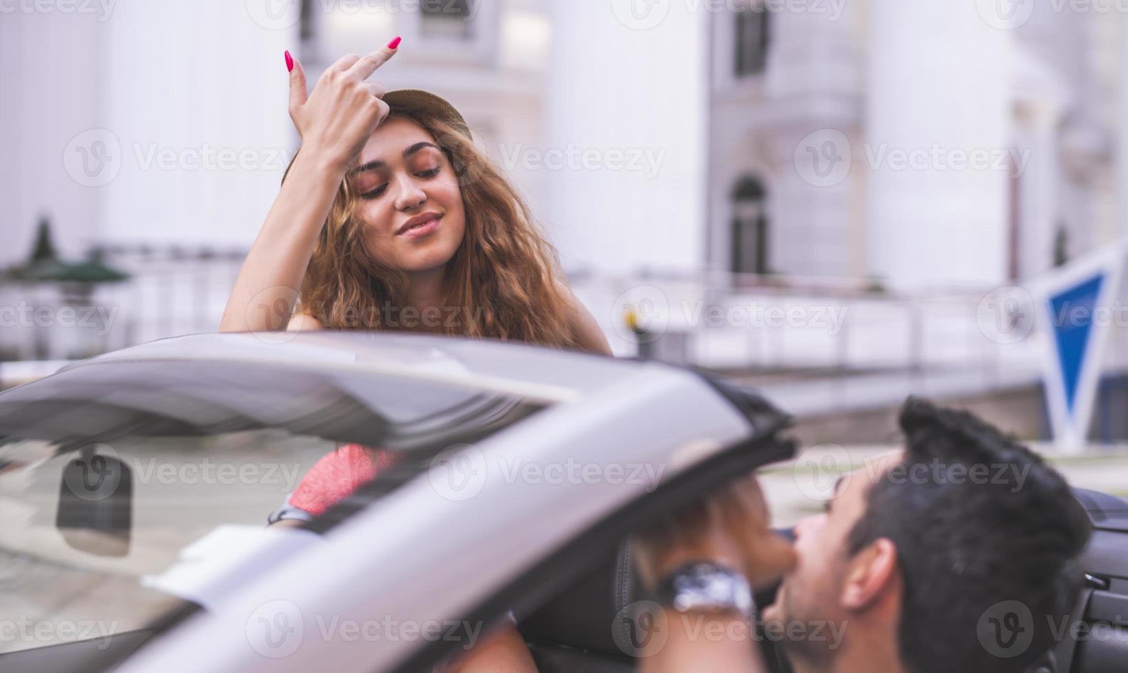 Happy young couple having fun in convertible car on beautiful summer day photo