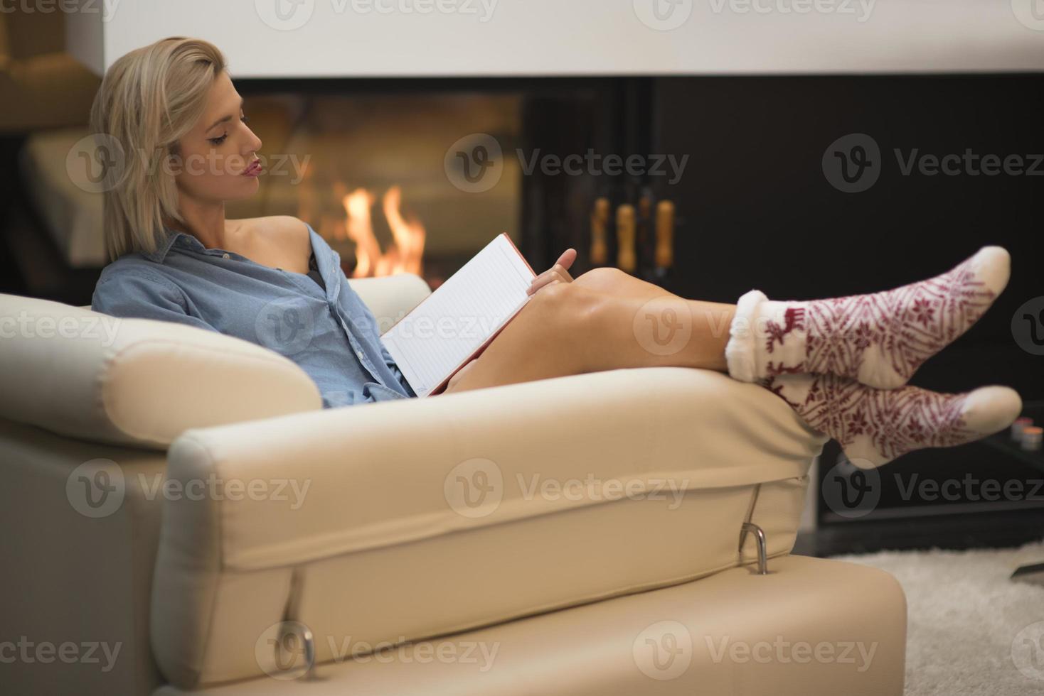 hermosa mujer leyendo un libro sentado en el sofá. foto