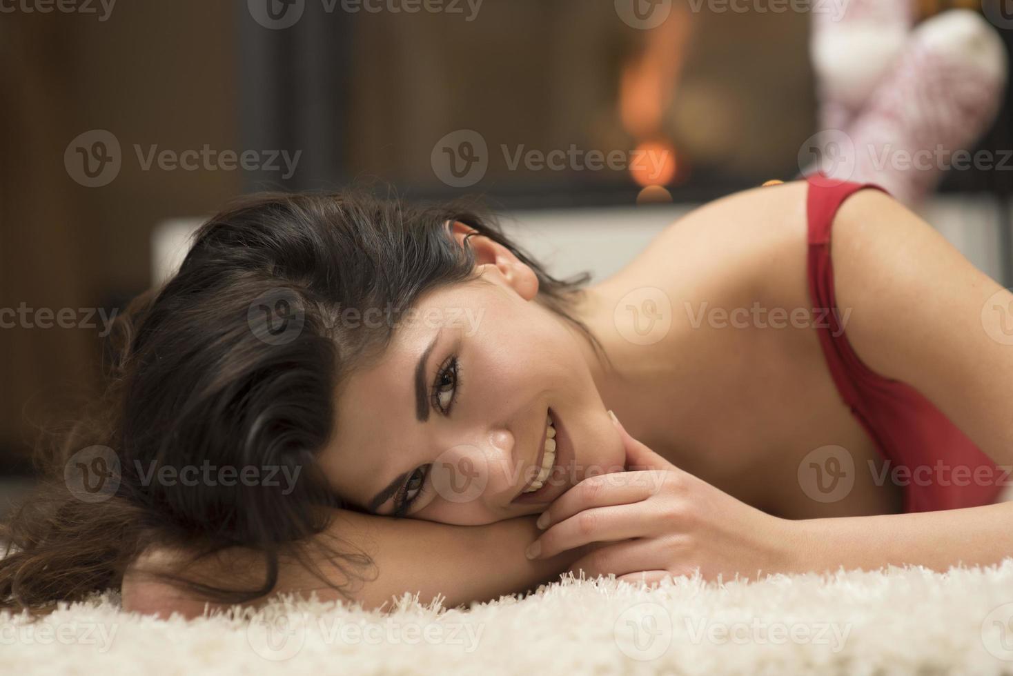 attractive brunette in red dress by a fireplace photo