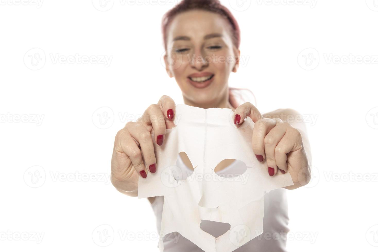 Face care and beauty treatments. Woman with a sheet moisturizing mask on her face isolated on white background photo