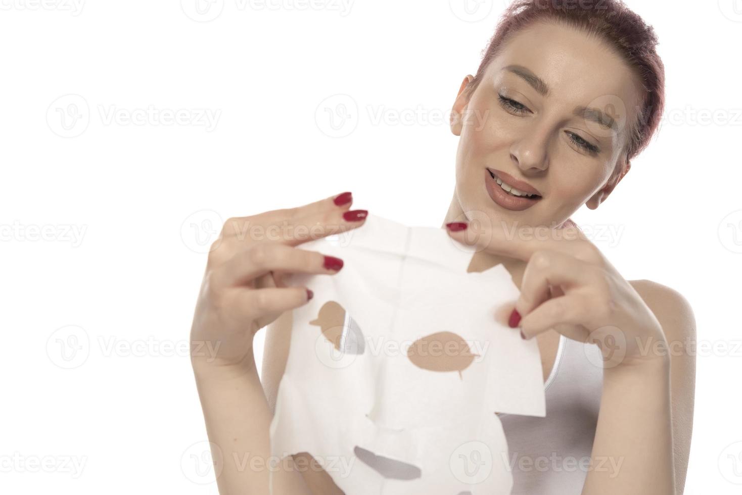 Face care and beauty treatments. Woman with a sheet moisturizing mask on her face isolated on white background photo