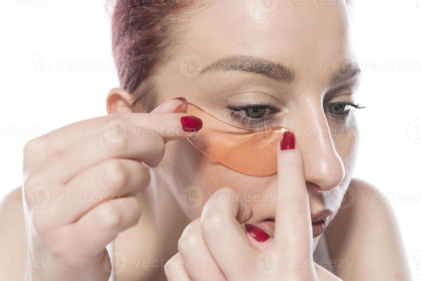 woman with cosmetic patches moisturizing on skin under eyes. isolated on white background photo