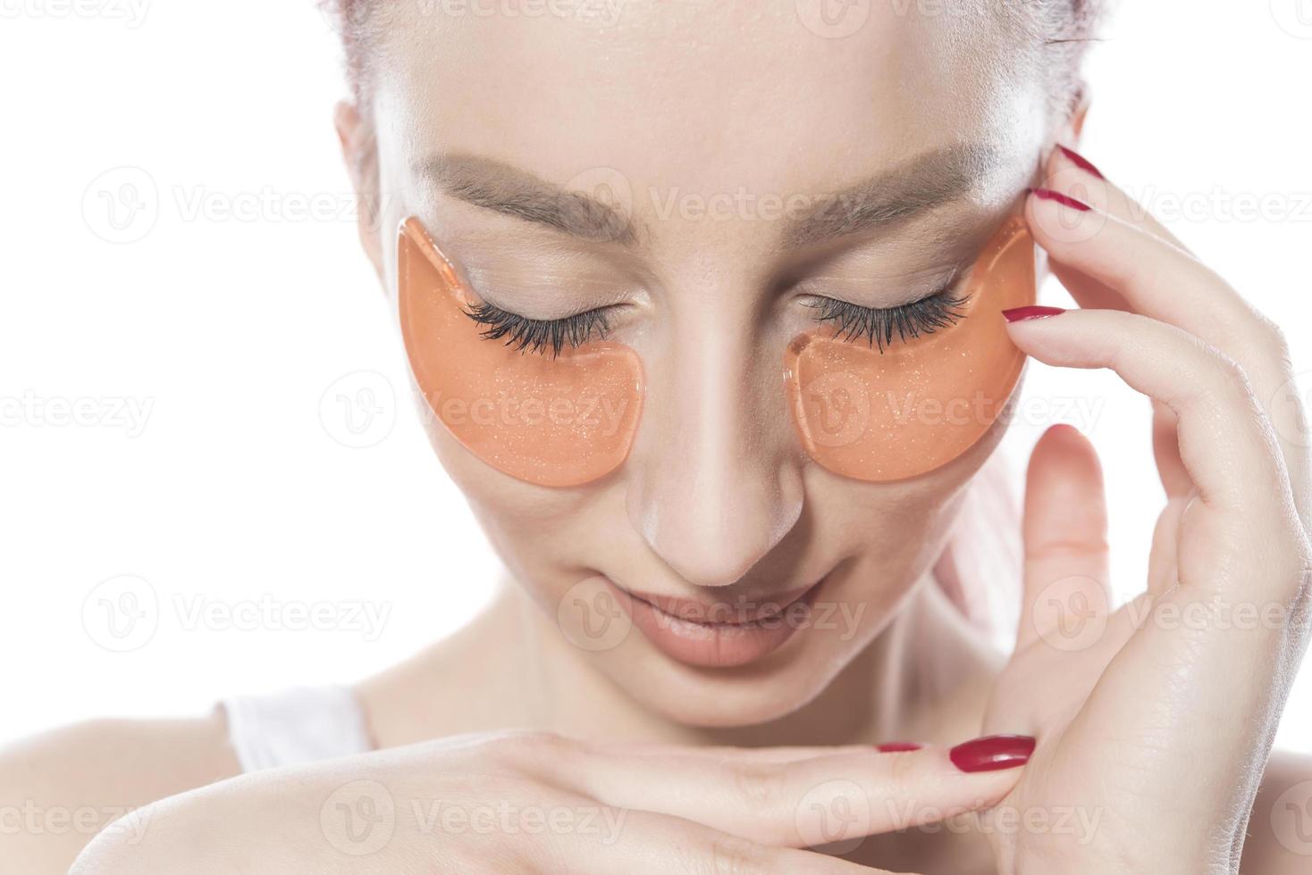 woman with cosmetic patches moisturizing on skin under eyes. photo