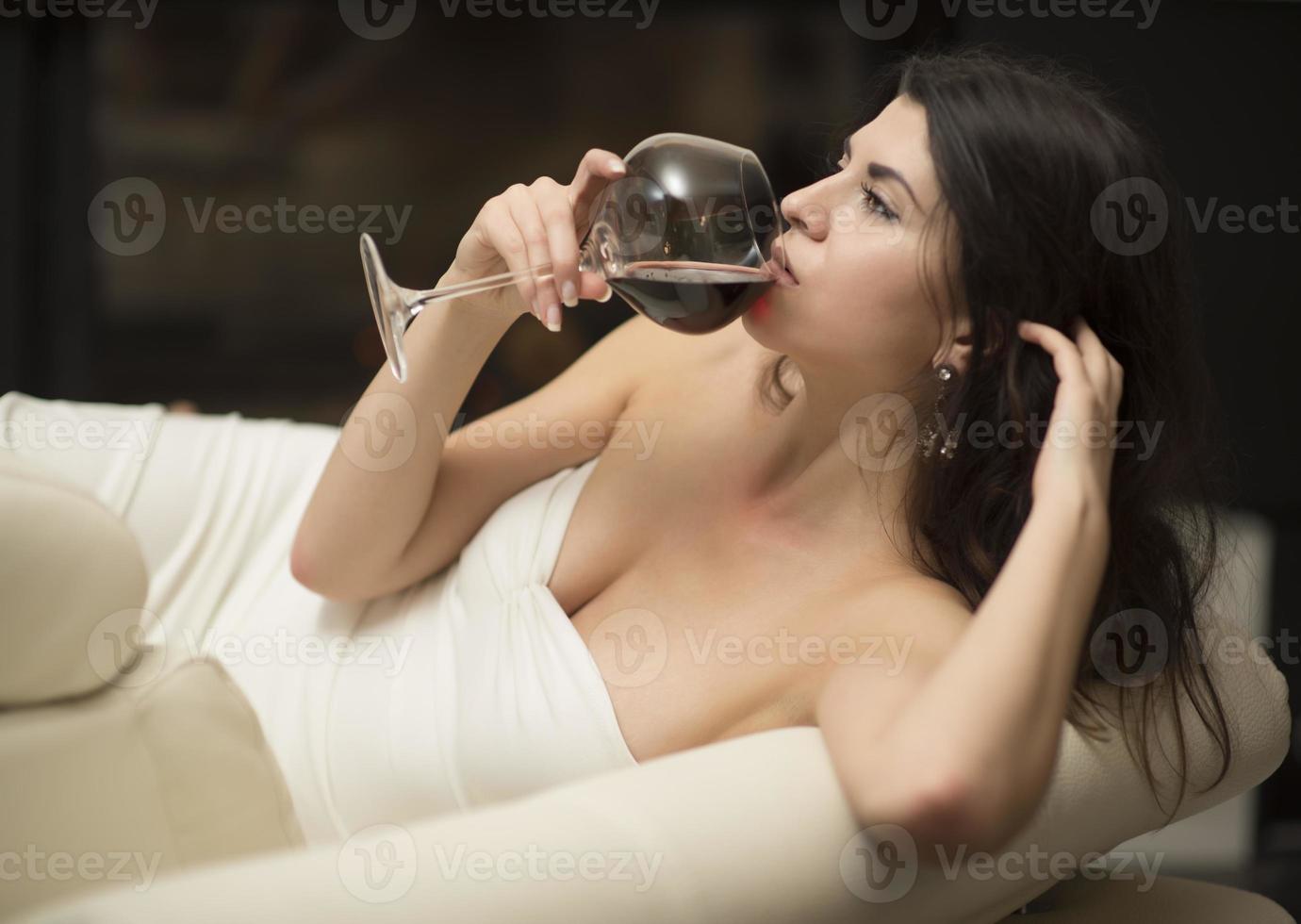 attractive brunette drinking wine by a fireplace photo