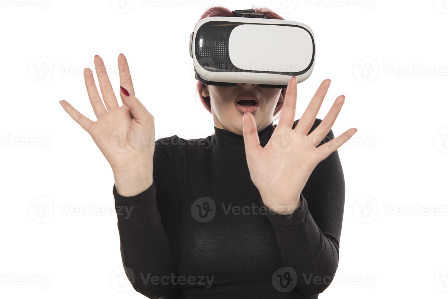 Pretty cute excited female in VR headset looking up and trying to touch objects in virtual reality photo