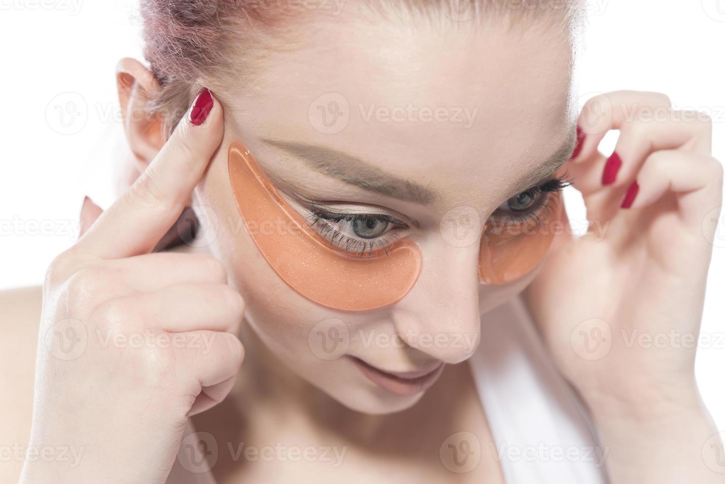 woman with cosmetic patches moisturizing on skin under eyes. photo