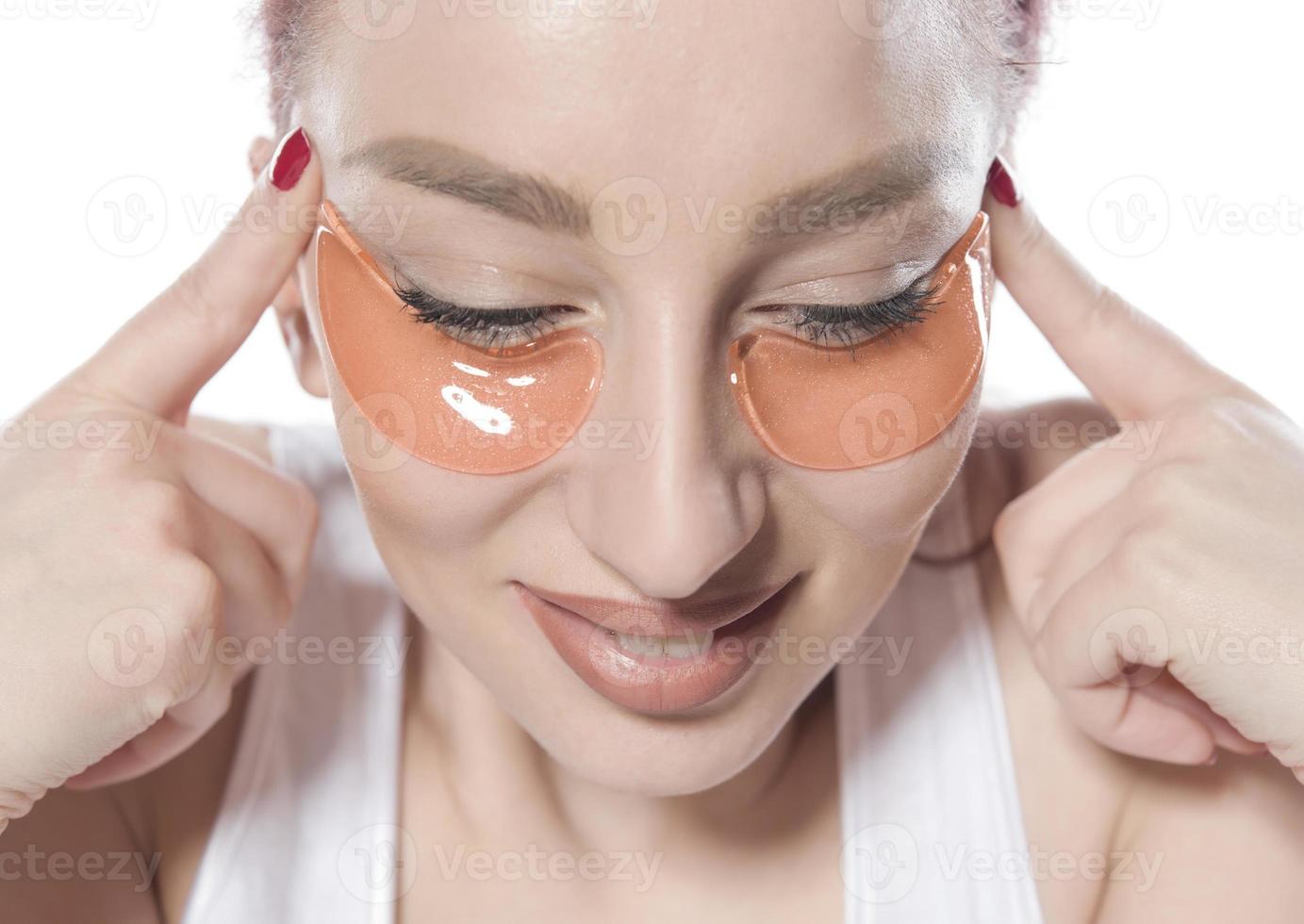 woman with cosmetic patches moisturizing on skin under eyes. photo