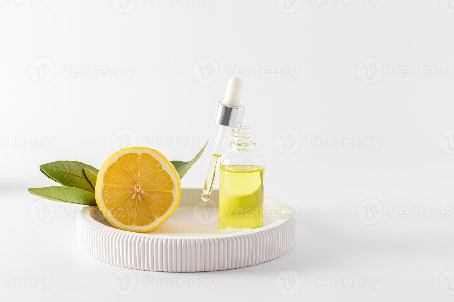 a natural organic facial skin care product based on lemon essential oil in a transparent bottle and pipette. white background. front view. photo