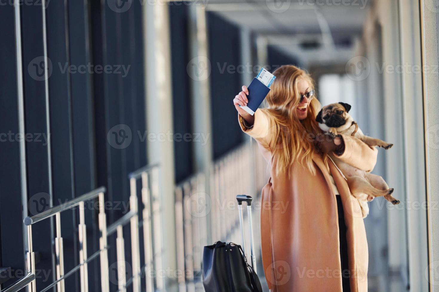 joven pasajera con ropa de abrigo caminando con su perro en el aeropuerto foto