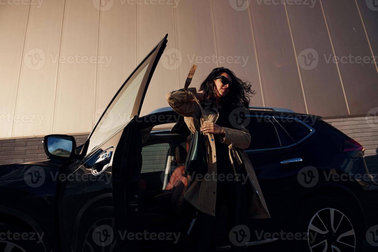 mujer joven en leggins negros sale de su coche moderno foto