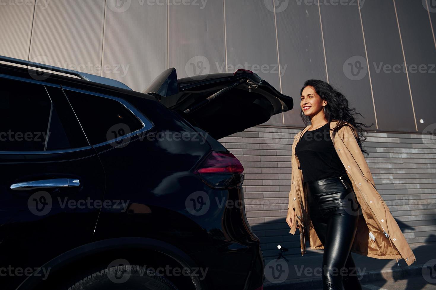 Young woman in black leggins walks out from her modern car photo