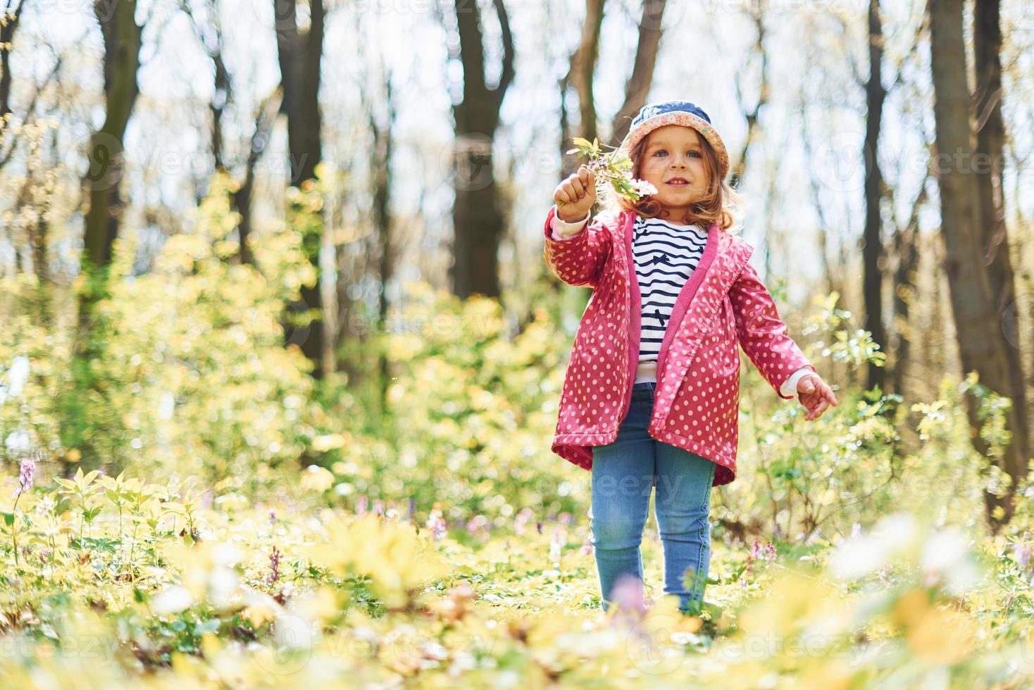 una niña feliz con sombrero azul tiene un paseo por el bosque de