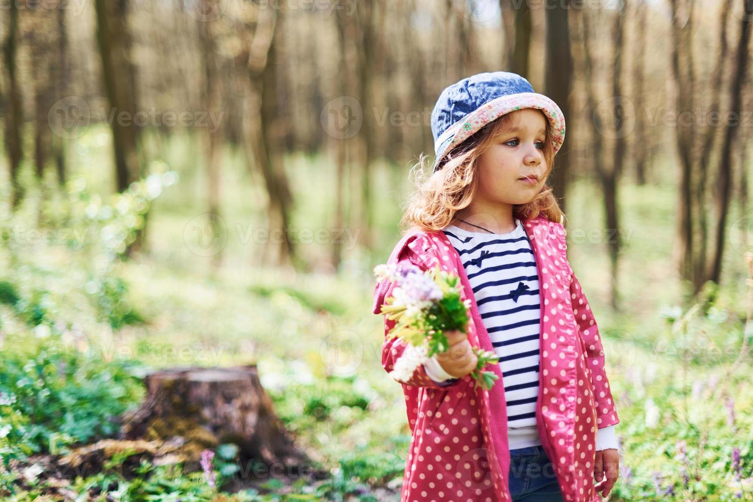 una niña feliz con sombrero azul tiene un paseo por el bosque de