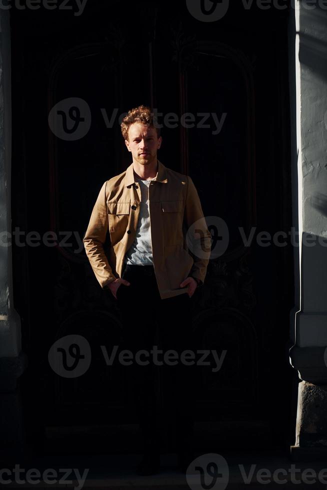 Elegant young man in formal classy clothes outdoors against black background photo