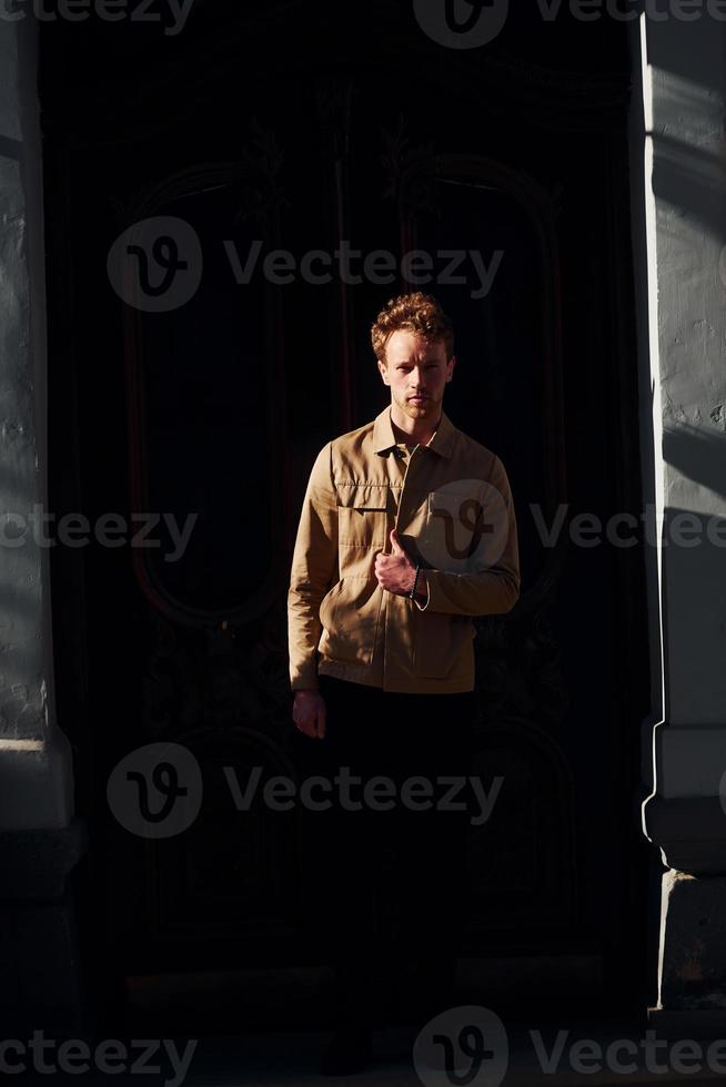 Elegant young man in formal classy clothes outdoors against black background photo