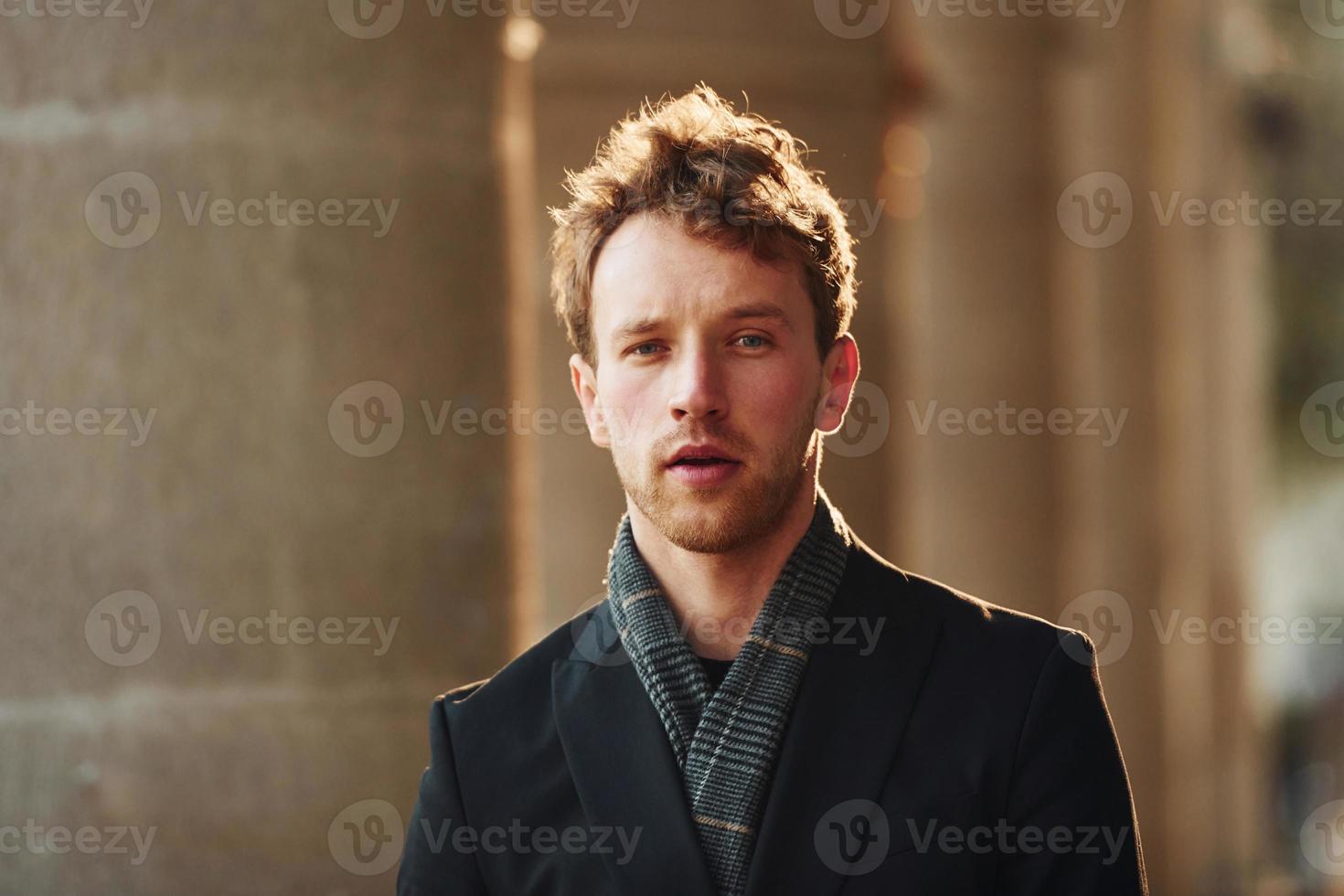 Portrait of elegant young man in formal classy clothes that outdoors in the city photo