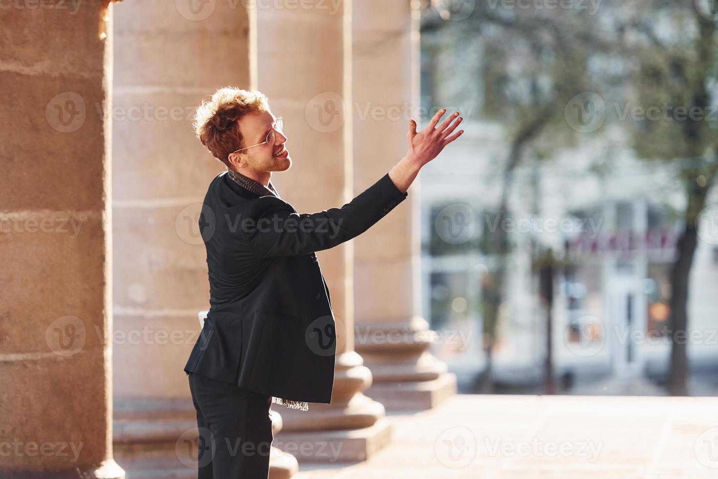 Talking to someone. Elegant young man in formal classy clothes outdoors in the city photo