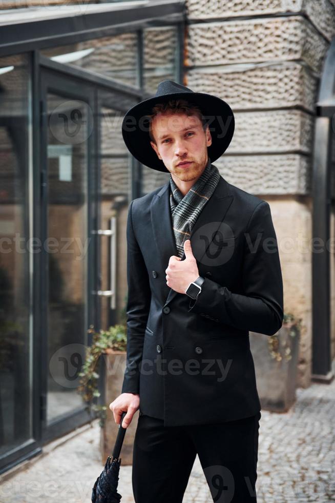elegante joven con sombrero negro y ropa con paraguas en las manos al aire libre la ciudad 15289073 Foto de stock en Vecteezy