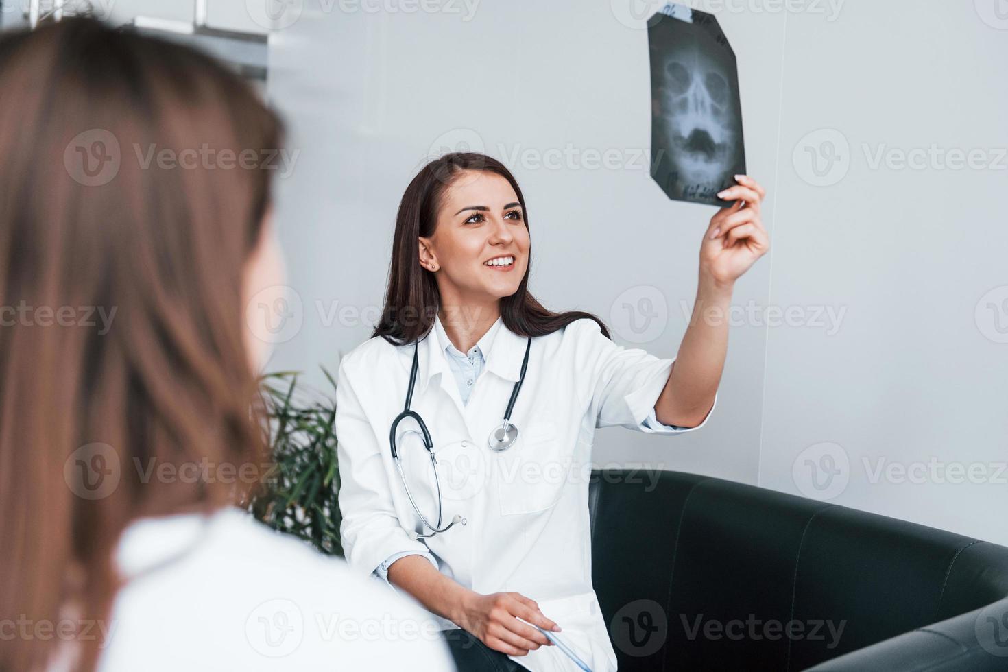 Shows results of x-ray. Young woman have a visit with female doctor in modern clinic photo