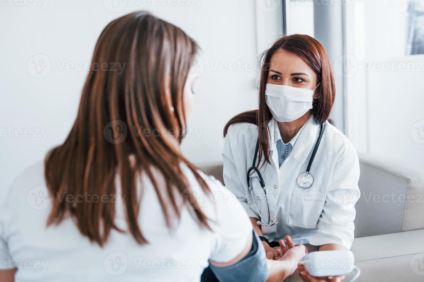 medir la presión arterial. una joven visita a una doctora en una clínica moderna foto