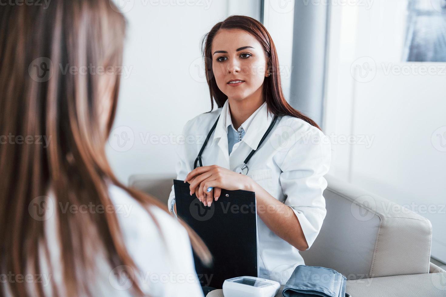 sentado y hablando. una joven visita a una doctora en una clínica moderna foto