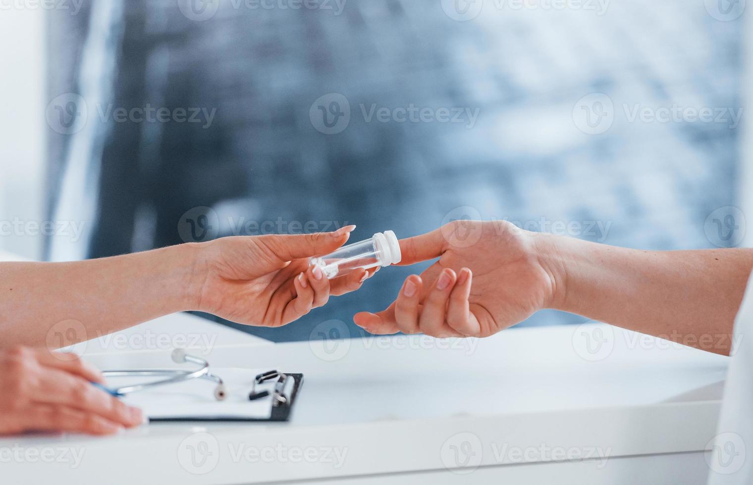 Doctor gives drugs to patient. Young woman have a visit with female doctor in modern clinic photo