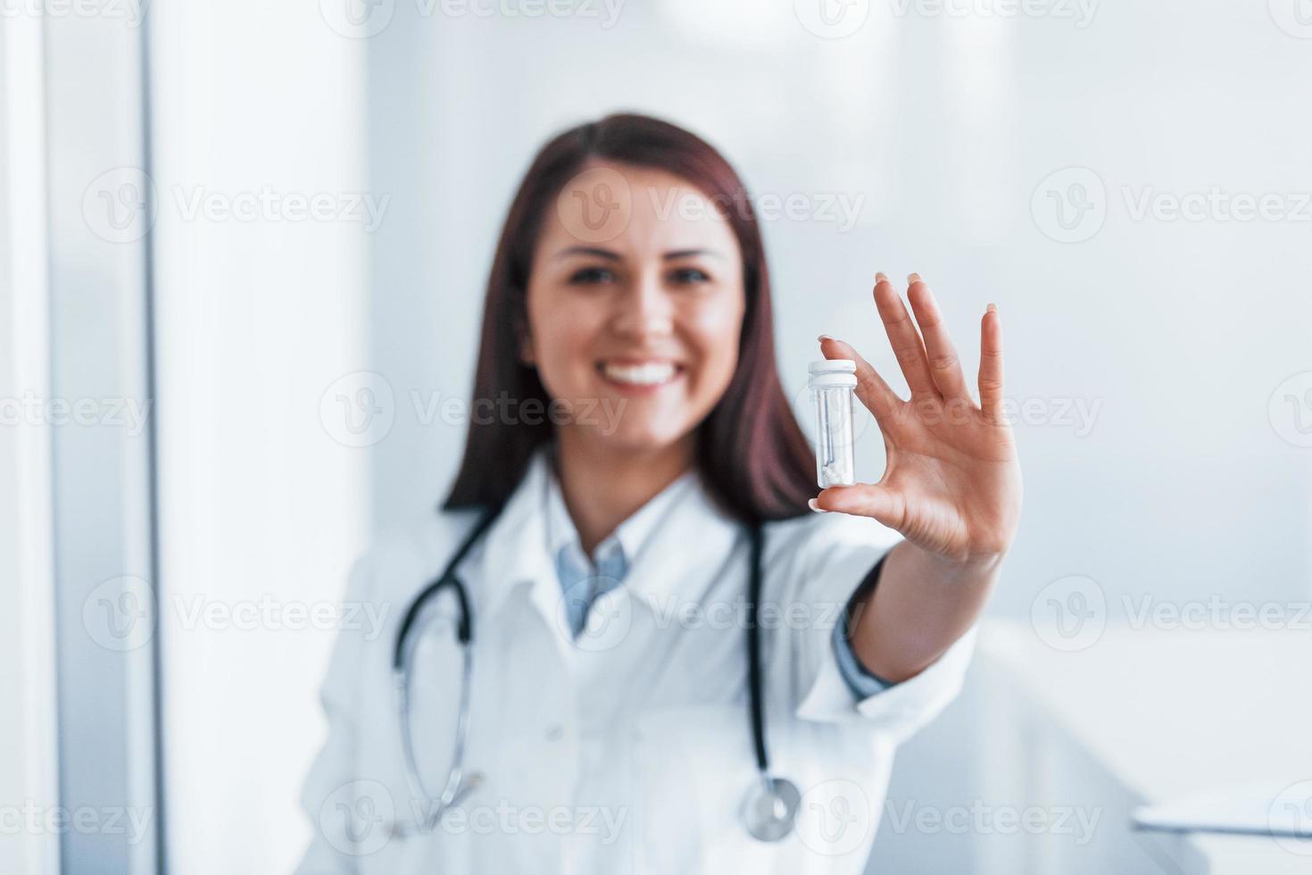 sosteniendo drogas en la mano. joven enfermera en el interior de una clínica moderna. concepción de la salud foto