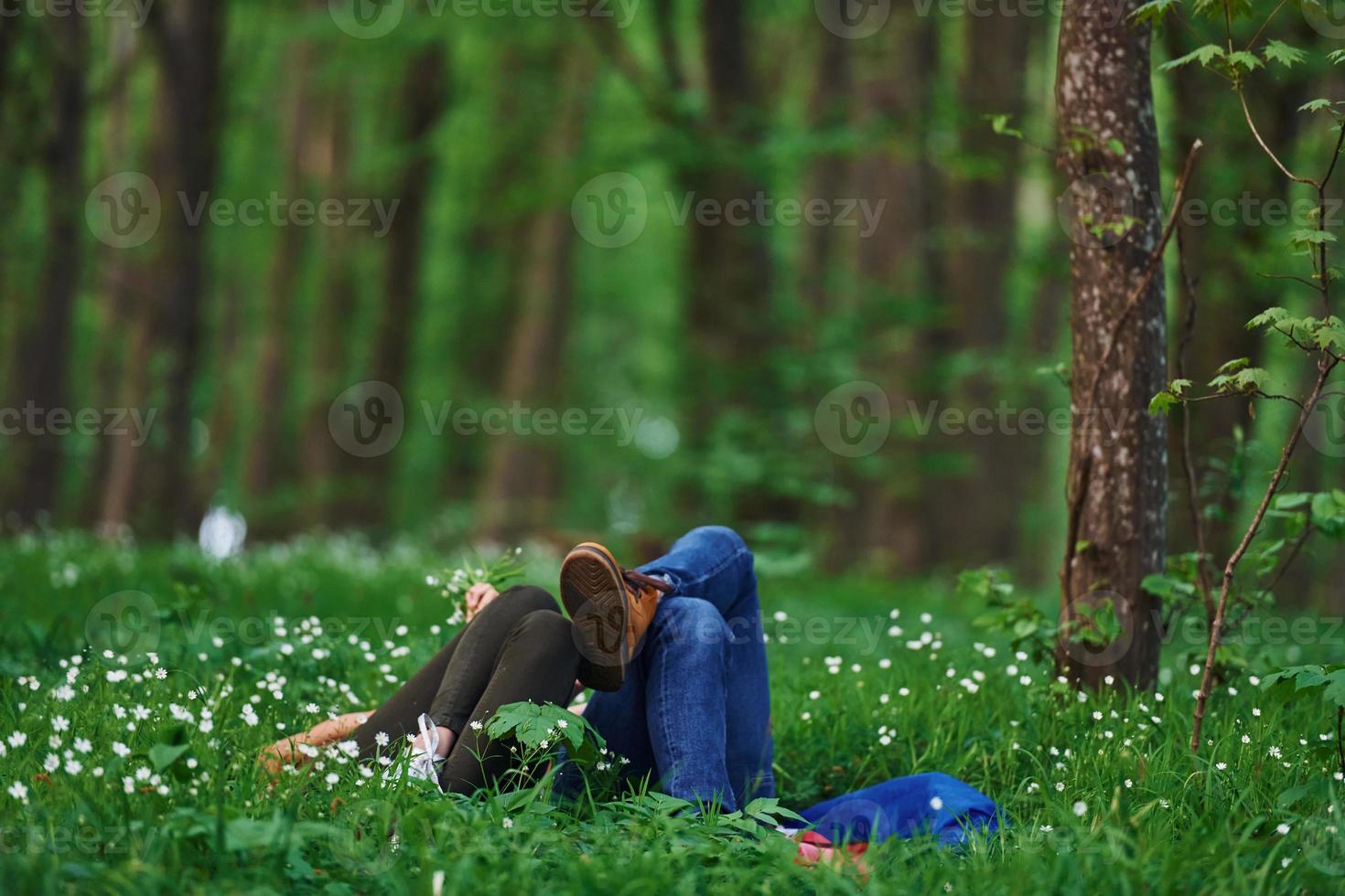 Couple lying down on the grass in forest together at daytime photo