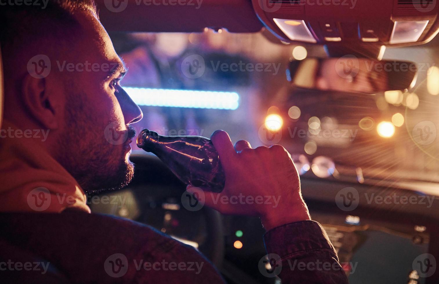 luces de policía negras y rojas. no bebas y manejes. vista trasera de un apuesto hombre sin afeitar con ropa de moda dentro de su automóvil foto