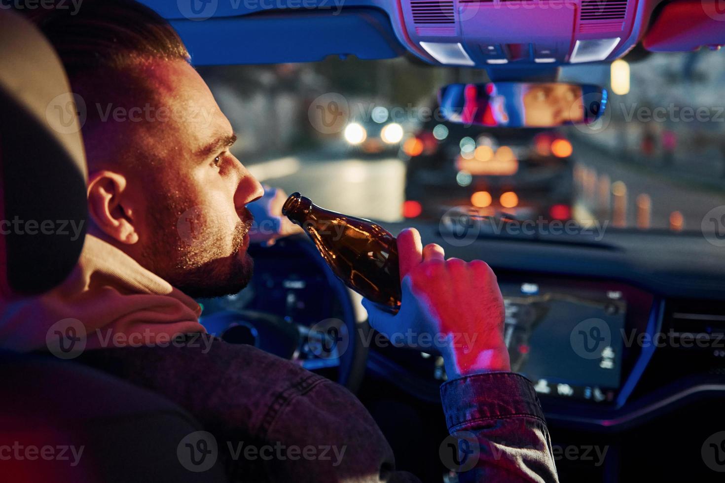 Black and red police lights. Dont drink and drive. Rear view of handsome unshaved man in fashionable clothes inside his automobile photo