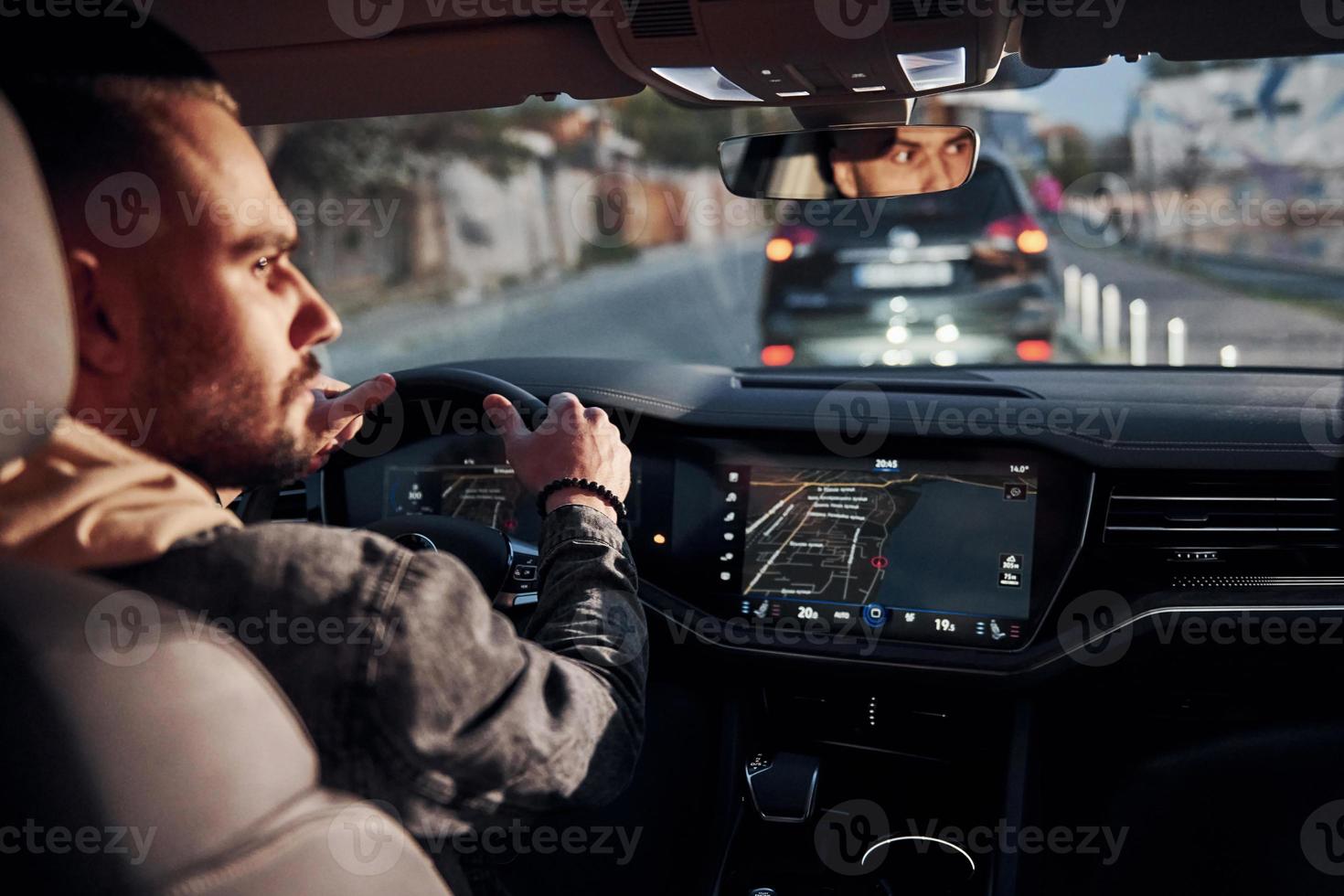 Rear view of handsome unshaved man in fashionable clothes that riding his automobile photo