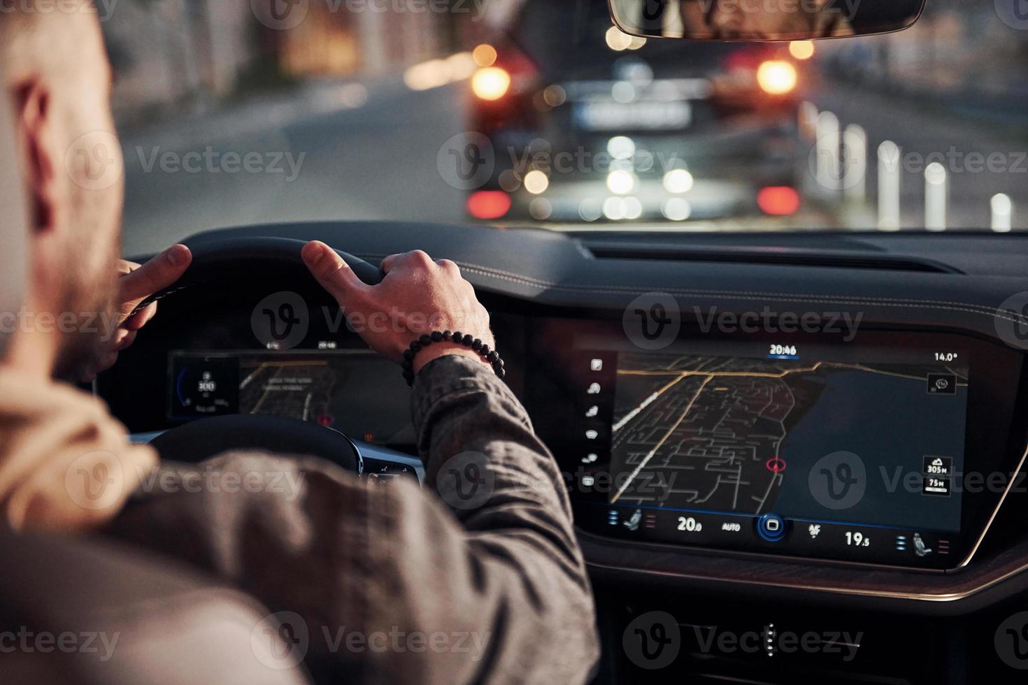 Rear view of handsome unshaved man in fashionable clothes that riding his automobile photo