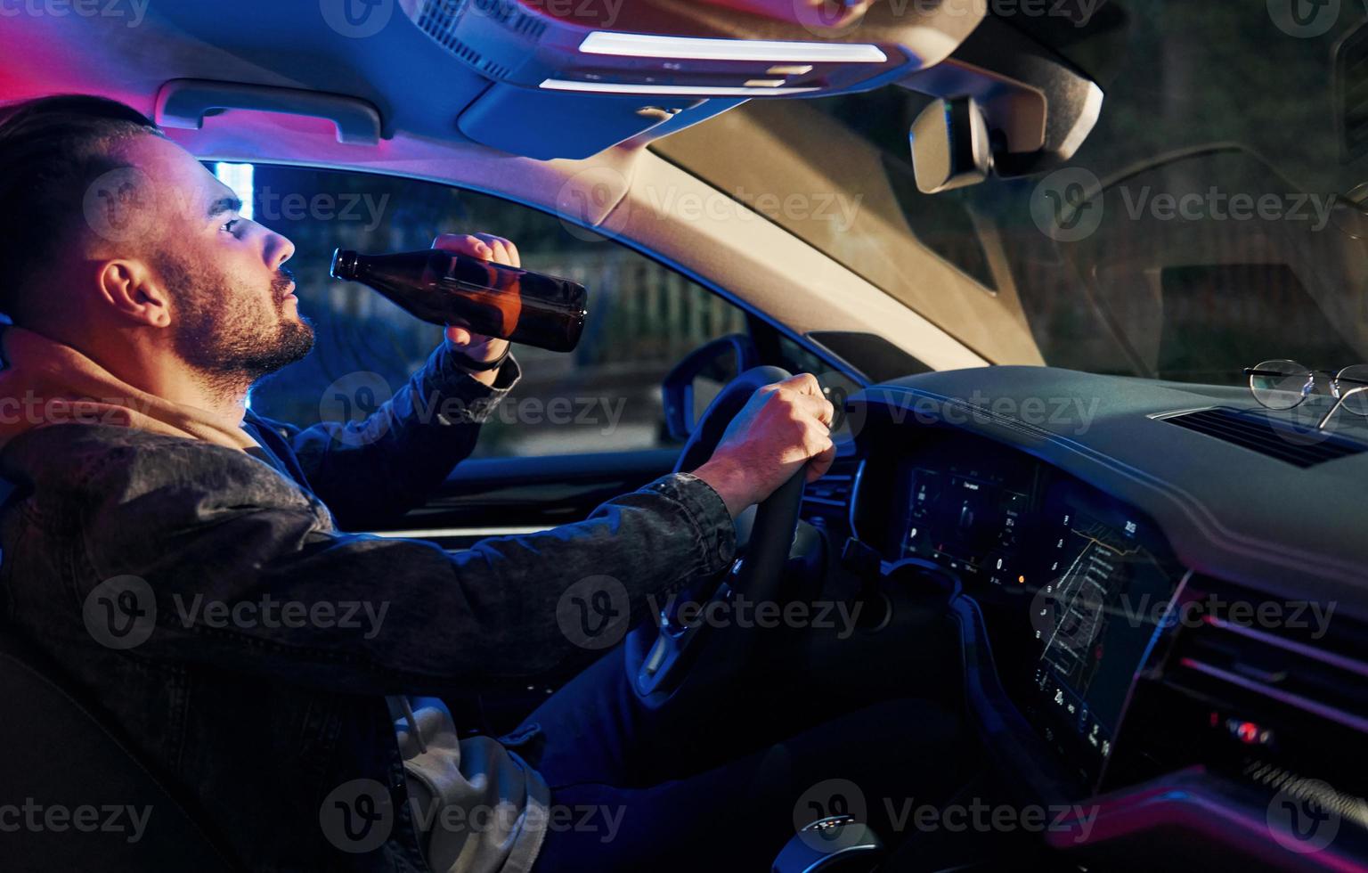 Black and red police lights. Dont drink and drive. Side view of handsome unshaved man in fashionable clothes inside his automobile photo