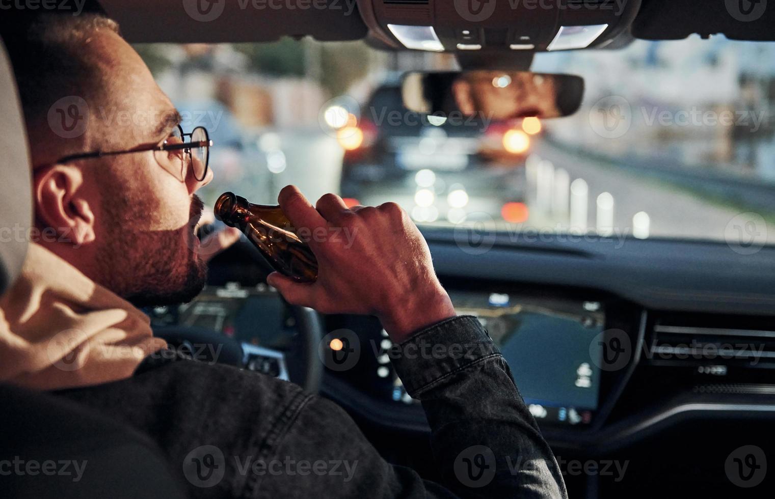 Dont drink and drive. Rear view of handsome unshaved man in fashionable clothes inside his automobile photo