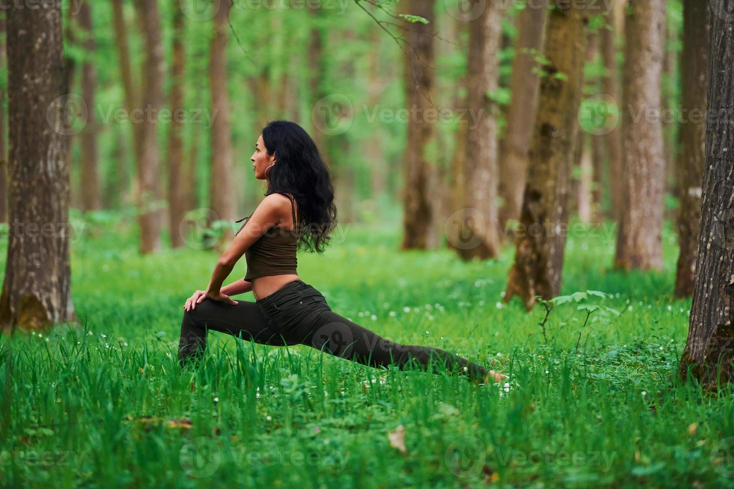 Positive brunette doing fitness outdoors in the forest at daytime photo