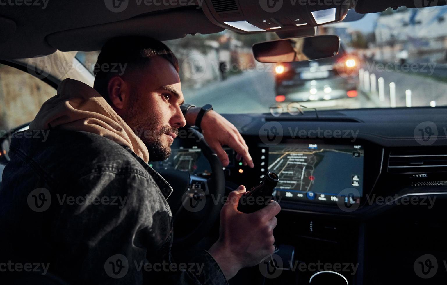 Dont drink and drive. Rear view of handsome unshaved man in fashionable clothes inside his automobile photo
