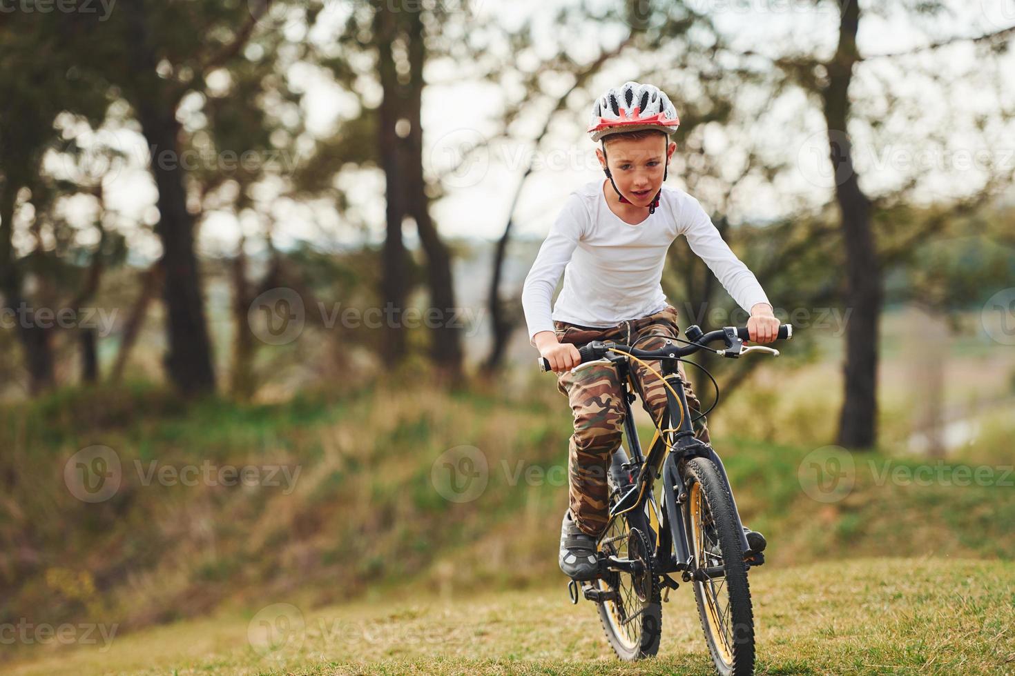 Young boy riding his bike outdoors in the forest at daytime photo