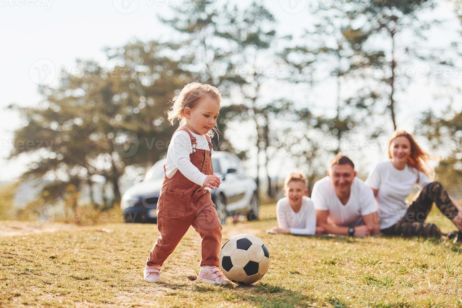 Happy family playing with soccer ball outdoors near the forest. With daughter and son photo