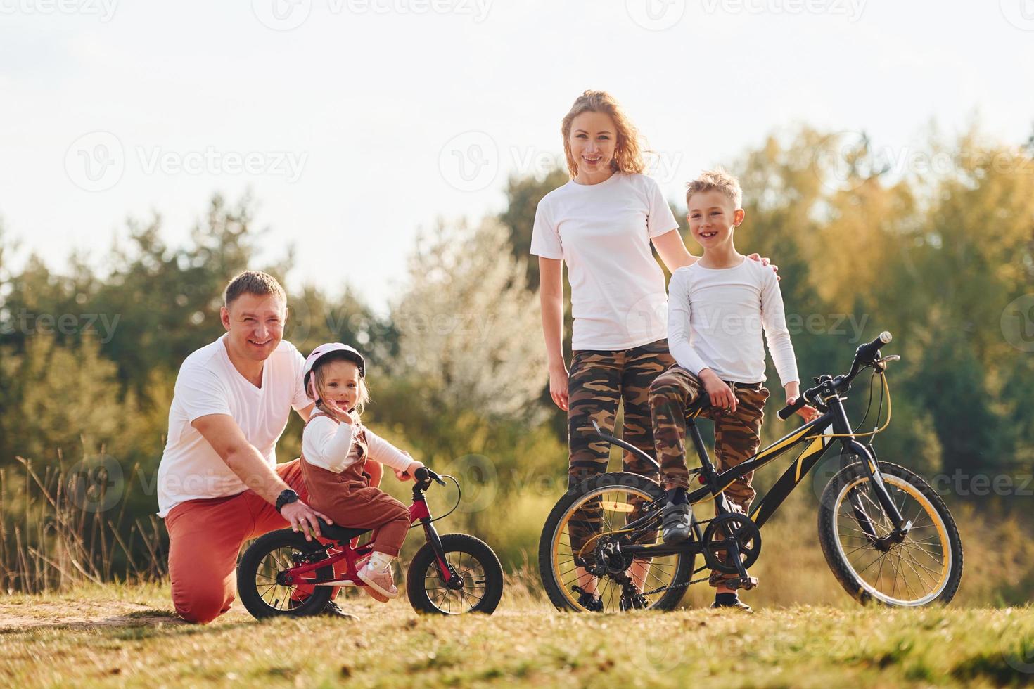 con bicicletas familia feliz pasando el fin de semana juntos al aire libre cerca del bosque. con hija e hijo foto