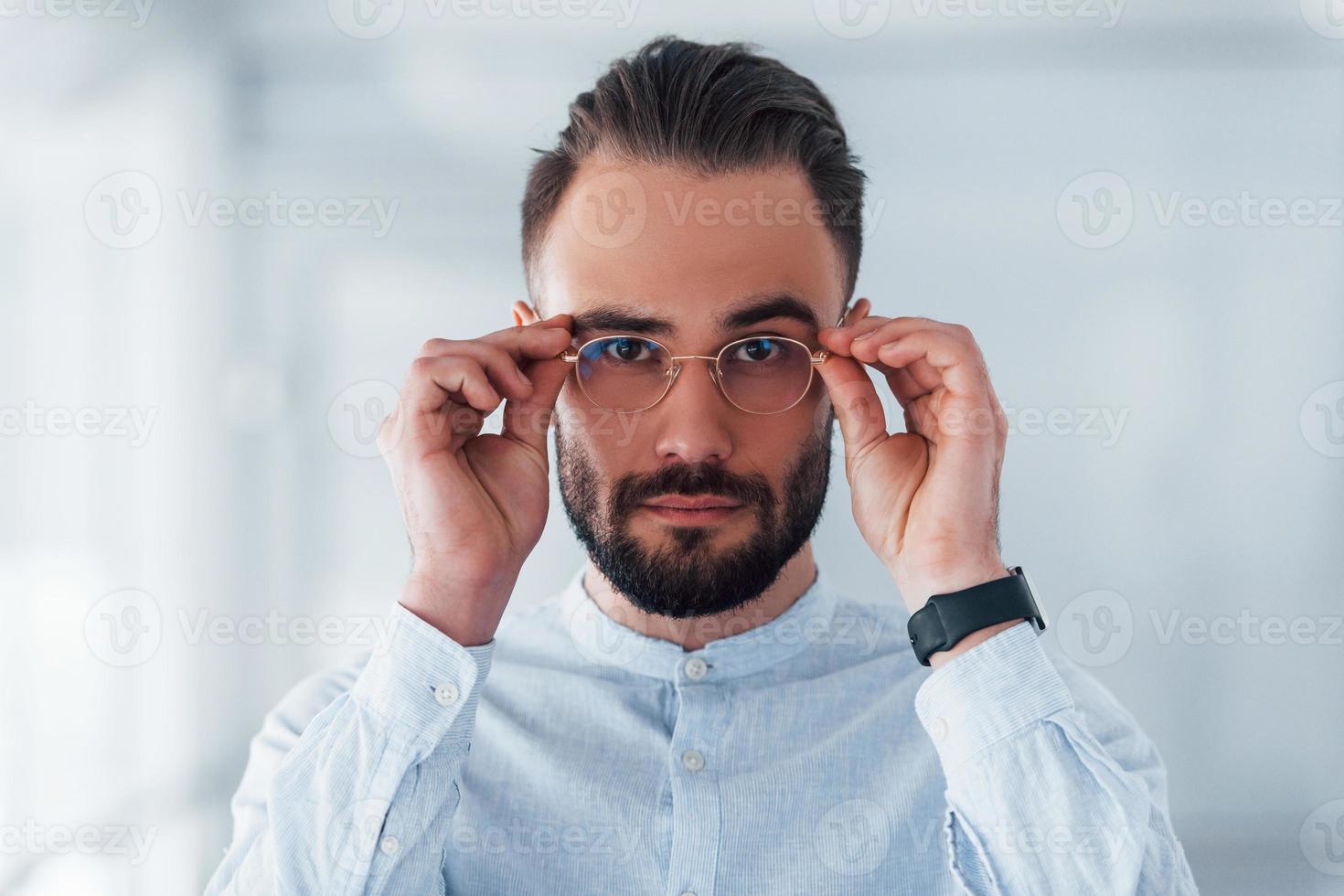 Portrait of young handsome man in formal clothes indoors in the office at daytime photo