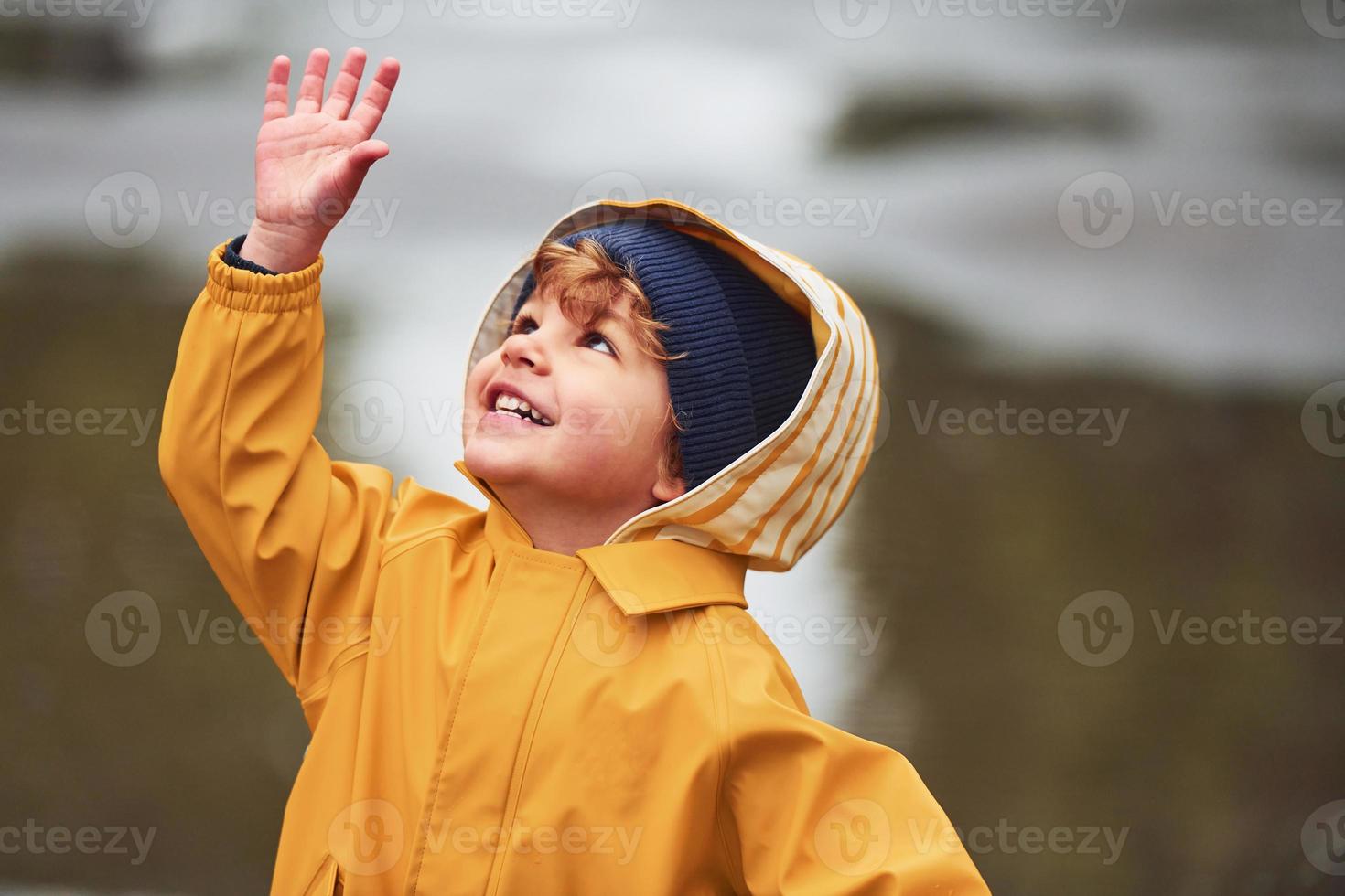 niño con capa impermeable amarilla y botas jugando al aire libre después de  la lluvia 15290286 Foto de stock en Vecteezy