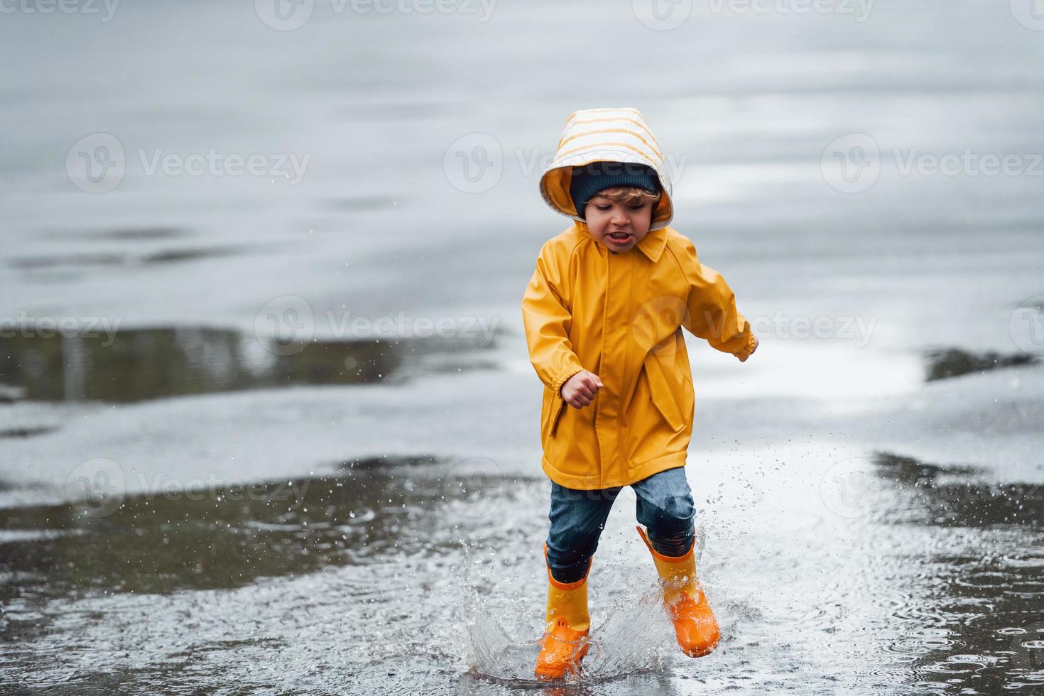 Un Niño Con Impermeable Amarillo Sale a La Lluvia. Solo Un Niño Camina Bajo  La Lluvia. Vista Posterior En Un Impermeable Brillante Imagen de archivo -  Imagen de cabritos, charco: 224329095