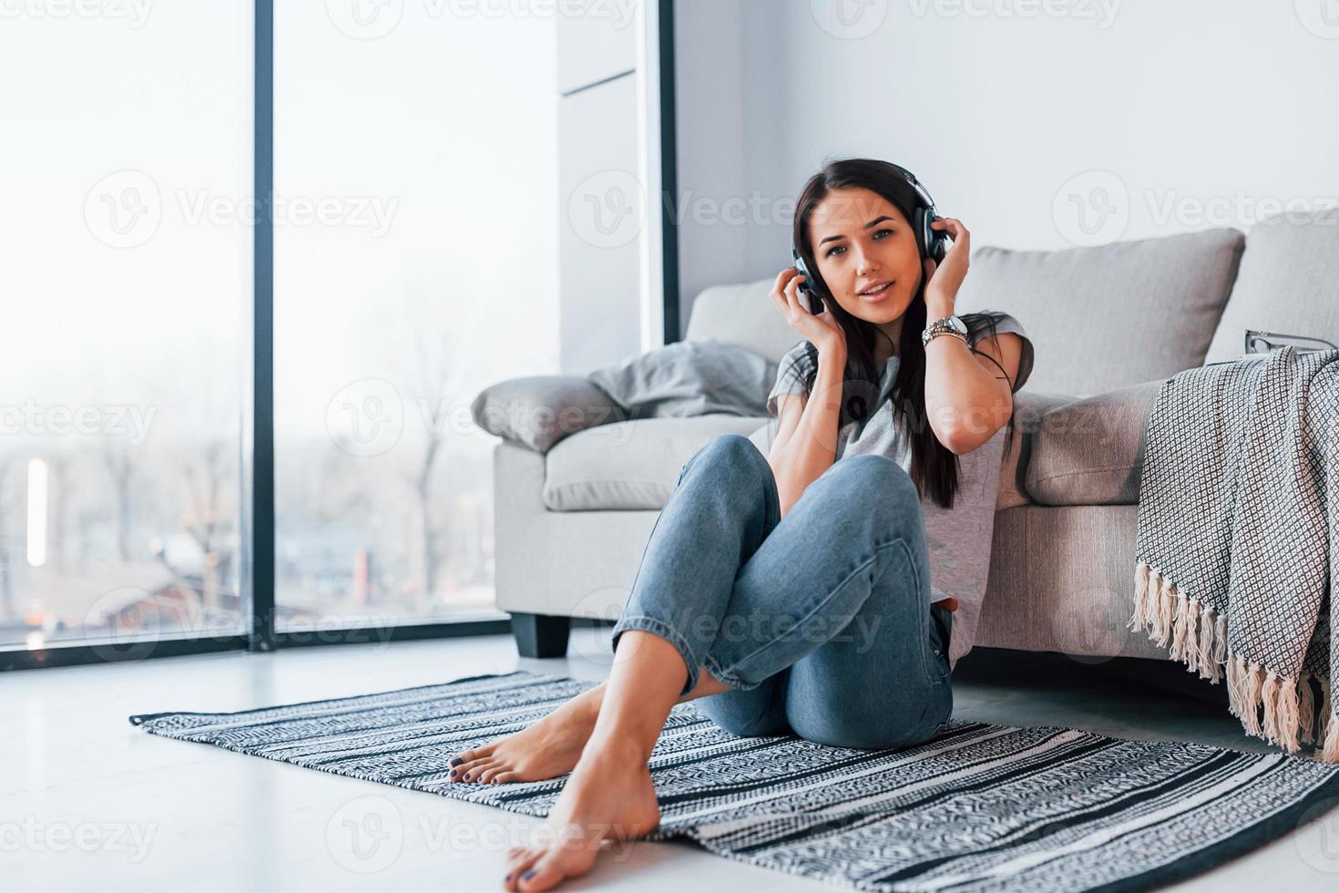 Young beautiful woman in casual clothes sitting at home alone and listening to the music in headphones photo