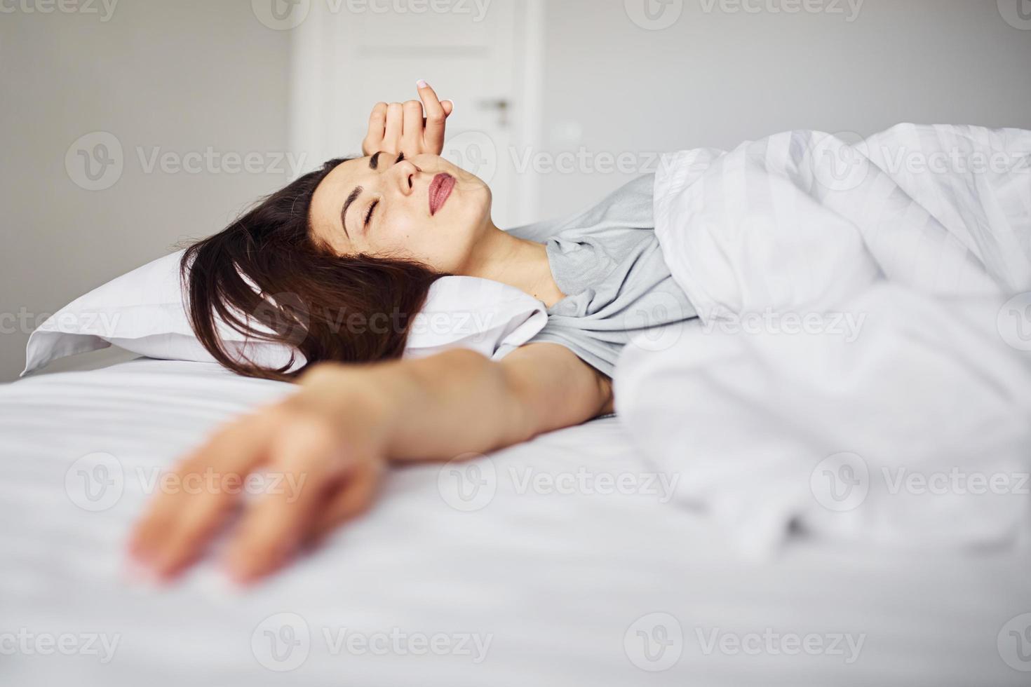 Sleeping on the bed. Young woman resting and spending weekend at home alone at home photo