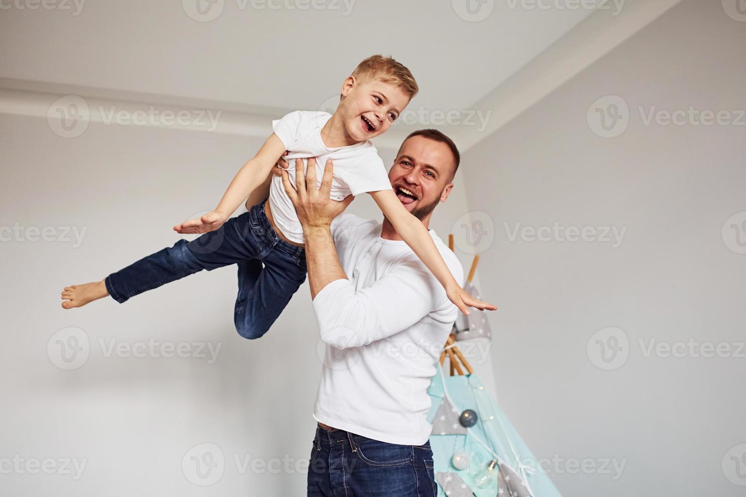 sosteniendo al niño en las manos. padre y su joven pasan tiempo juntos en el interior cerca de la tienda foto
