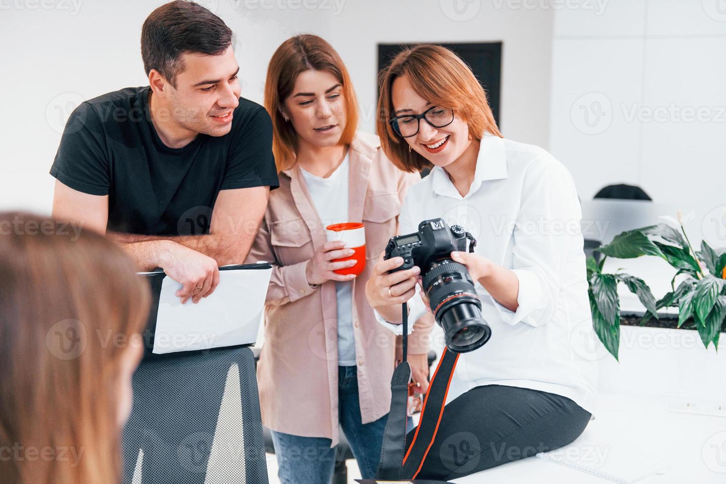Group of business people in formal clothes indoors in the office looking at photos on the camera