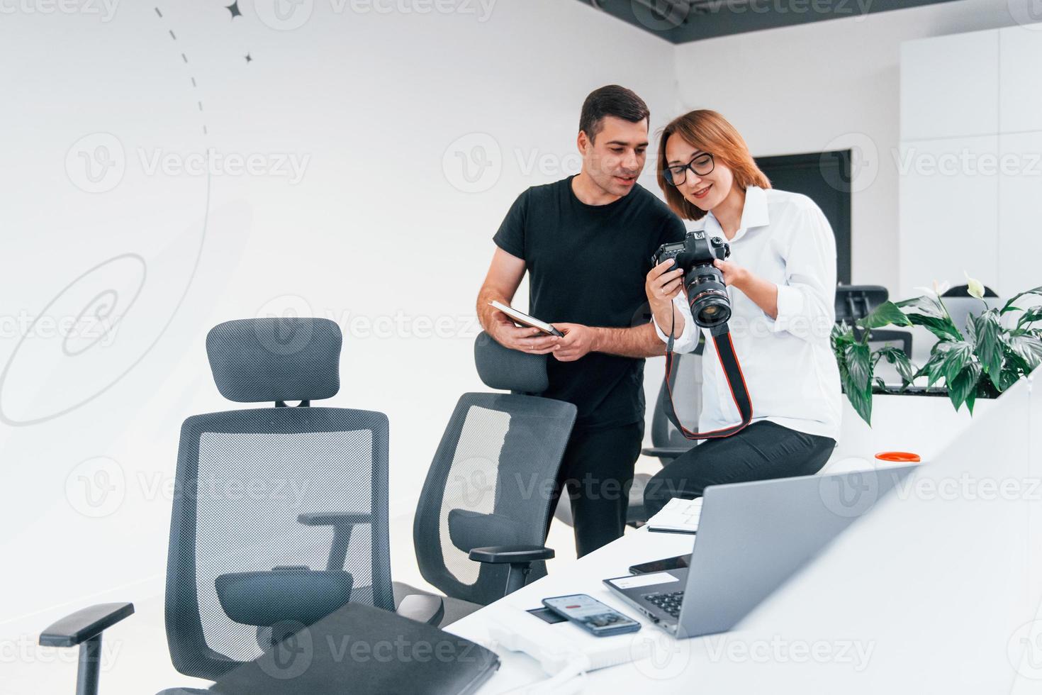 Man in black clothes watching photos on the female's photographer camera