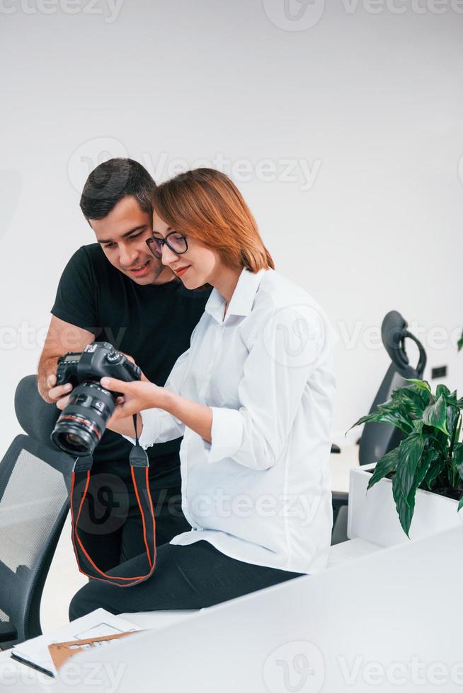 hombre vestido de negro viendo fotos en la cámara del fotógrafo femenino