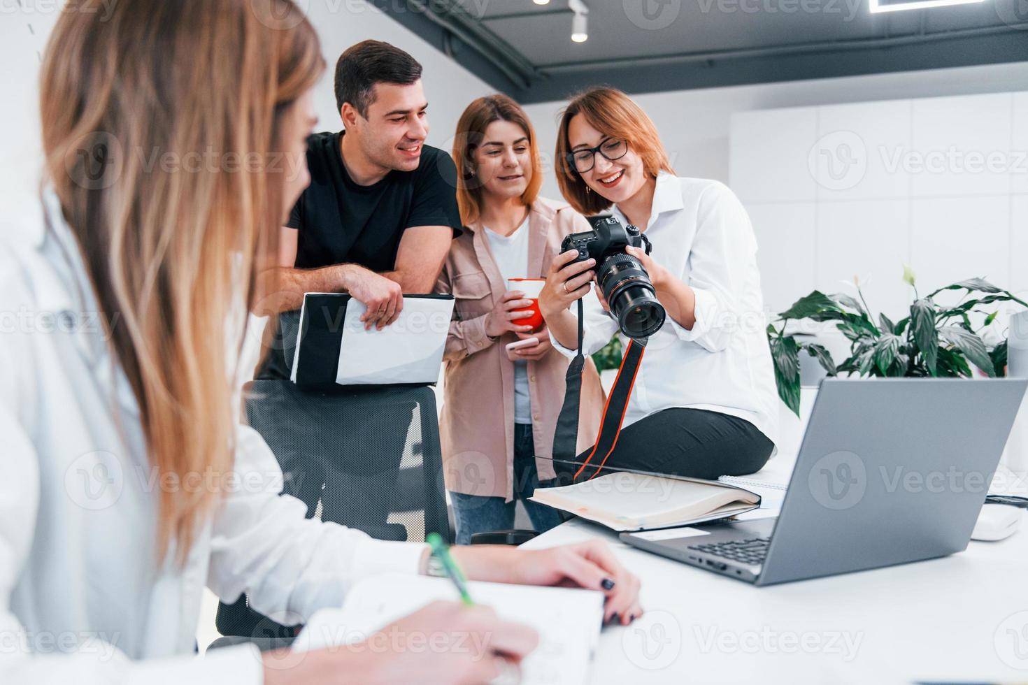 Group of business people in formal clothes indoors in the office looking at photos on the camera