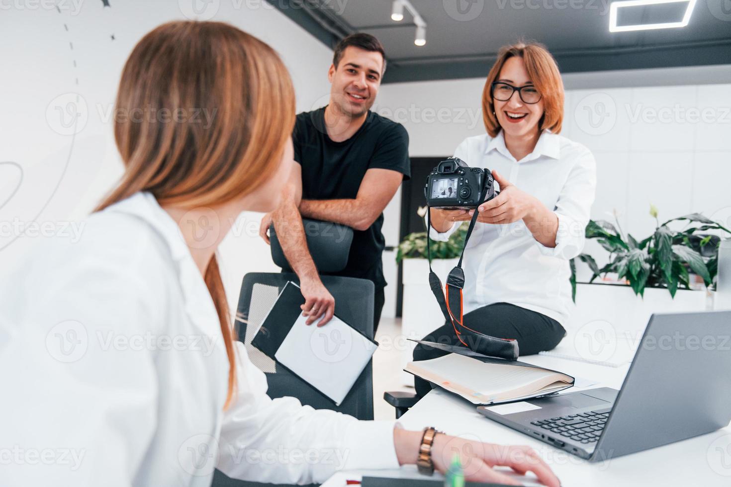 Group of business people in formal clothes indoors in the office looking at photos on the camera